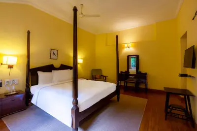 a bedroom with a four poster bed and a desk at amã Stays & Trails - Cottabetta Bungalow, Coorg in Gonikoppal