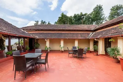 a patio with a table and chairs on it at amã Stays & Trails - Cottabetta Bungalow, Coorg in Gonikoppal