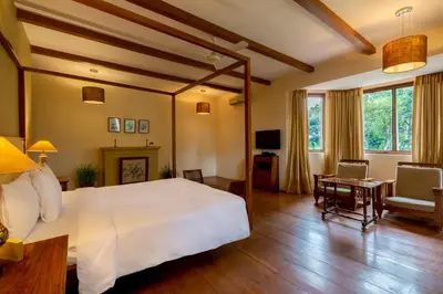 a bedroom with a large white bed and a desk at amã Stays & Trails - Taneerhulla Bungalow, Coorg in Titimati