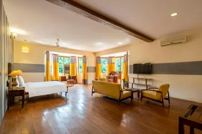 a bedroom with a bed and a living room at amã Stays & Trails - Taneerhulla Bungalow, Coorg in Titimati