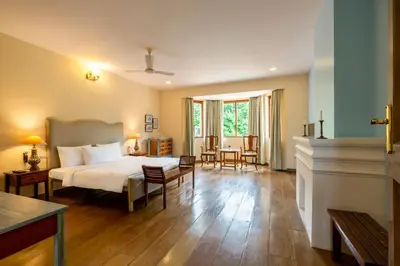 a bedroom with a bed and a living room at amã Stays & Trails - Taneerhulla Bungalow, Coorg in Titimati