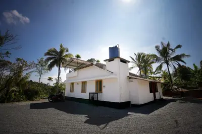 a white house with palm trees in the background at Stay Vista in Mananthavady