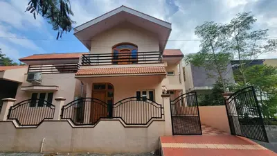 a large house with a gate in front of it at Aasana A tranquil space by the hills in Mysore
