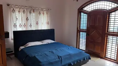 a bedroom with a blue bed and two windows at Aasana A tranquil space by the hills in Mysore