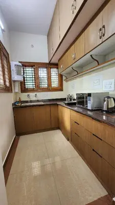 a large kitchen with wooden cabinets and counters at Aasana A tranquil space by the hills in Mysore