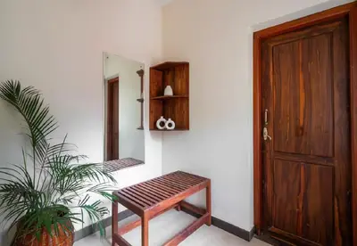 a wooden door and a bench next to a plant at Enteveedu Homestay in Panamaram