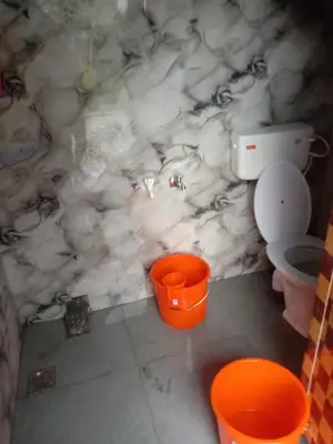 a marble bathroom with a toilet and two orange buckets at Vattavada Homestay in Vattavada