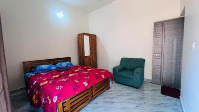 a bedroom with a bed and a green chair at Chemperi Residency in Paithalmala