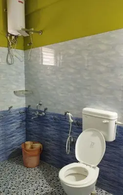 a bathroom with a white toilet in a room at VR Home Stay Ooty in Ooty