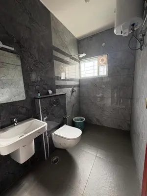 a bathroom with a white toilet and a sink at BBR Residency in Ooty