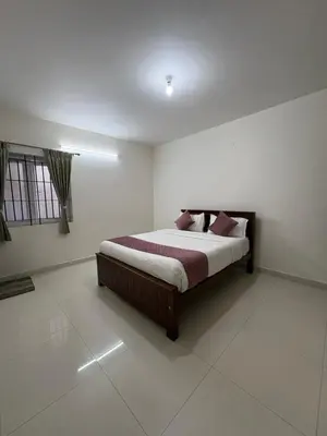 a bedroom with a bed in a white room at BBR Residency in Ooty