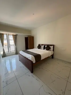 a bedroom with a bed and a large window at BBR Residency in Ooty