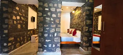 a room with a bed and a stone wall at Elephant County Resort in Masinagudi