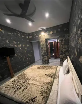 a bedroom with a bed in a room with stone walls at Elephant County Resort in Masinagudi