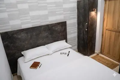 a white bed with a cross and a book on it at Aldhi Residency in Perintalmanna