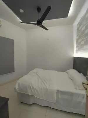 a bedroom with a bed with a ceiling fan at Aldhi Residency in Perintalmanna