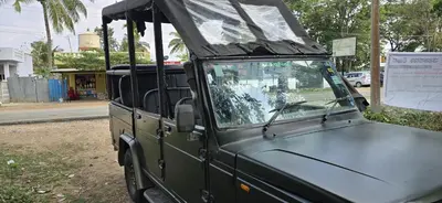 a green jeep with its roof up on a street at Tiger Woods Homestay Kabini in Antarasante