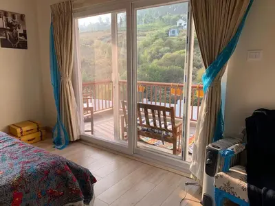 a bedroom with a large sliding glass door to a deck at Neom Valley Stays in Ketti