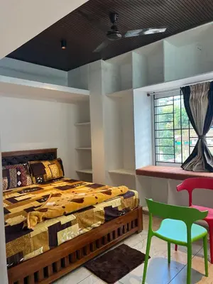 a bedroom with a bed and a green chair at Village Villa in Vālpārai