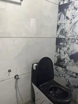 a bathroom with a black toilet in a wall at Village Villa in Vālpārai