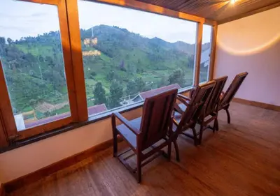 a room with a table and chairs and a large window at Mandarin Orchid Resort in Kotagiri