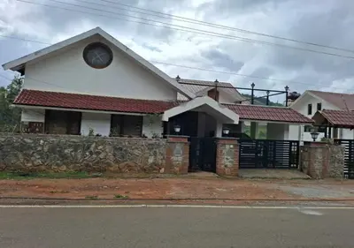 a white house with a fence and a clock on it at Mandarin Orchid Resort in Kotagiri