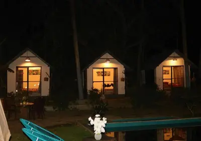 two cottages at night with a pool in front at The Wildcamp - Coorg in Kushālnagar