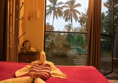 a towel on top of a bed with a window at The Wildcamp - Coorg in Kushālnagar