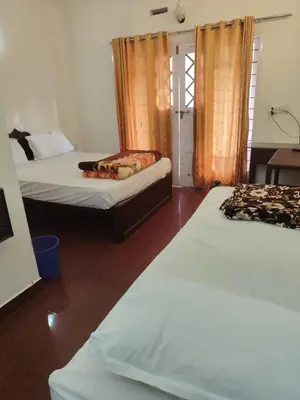 a hotel room with two beds and a table and a room at Kurinji home stay munnar in Munnar