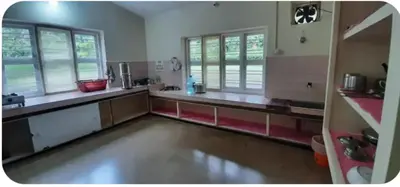 a large kitchen with stainless steel counters and windows at Nakoor volkot in Suntikoppa