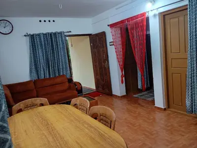 a living room with a table and a couch at Enjoy home stay in Vattavada