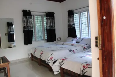 two beds in a room with windows at The H and S Stays in Madikeri