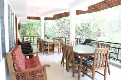a porch with a table and chairs on a balcony at The H and S Stays in Madikeri