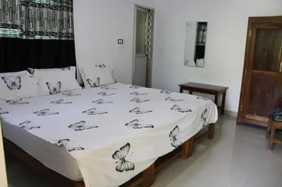 a bedroom with a bed with a white comforter at The H and S Stays in Madikeri