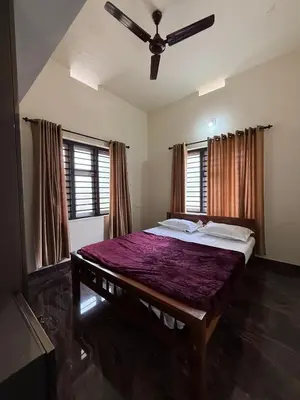 a bedroom with a large bed with a ceiling fan at AP'S Homestay Nilambur in Nilambūr