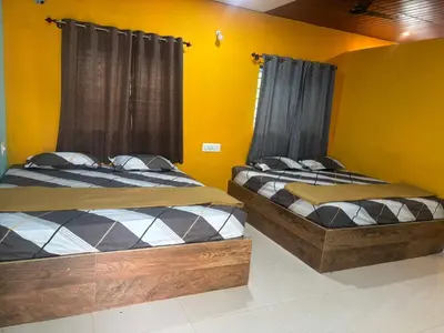 two beds in a room with yellow walls at Aryas comforts Sri Rangapattana in Nāganahalli