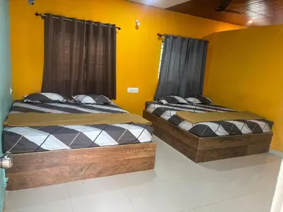two beds in a room with yellow walls at Aryas comforts Sri Rangapattana in Nāganahalli