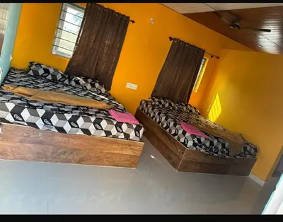 two beds in a room with yellow walls at Aryas comforts Sri Rangapattana in Nāganahalli