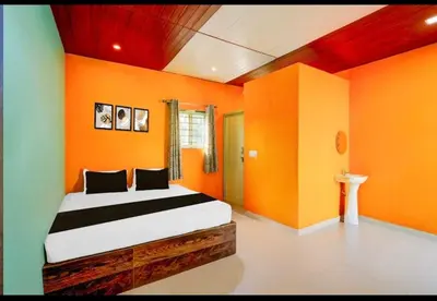 a bedroom with orange walls and a bed in it at Aryas comforts Sri Rangapattana in Nāganahalli