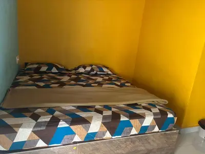 a bed in a room with a yellow wall at Aryas comforts Sri Rangapattana in Nāganahalli