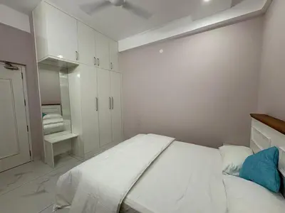 a white bedroom with a large bed and white cabinets at Evania Pool Suites in Nedumbassery