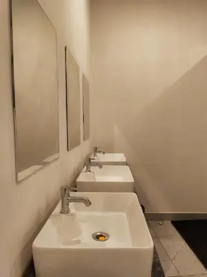 a bathroom with three white sinks and a mirror at Thekkini rooms and Dorms in Kozhikode