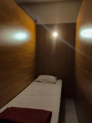 a small room with a bed and a light on the wall at Thekkini rooms and Dorms in Kozhikode