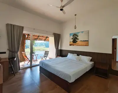 a bedroom with a large bed and a balcony at Vaigayi Ayurveda Resort in Kodanad