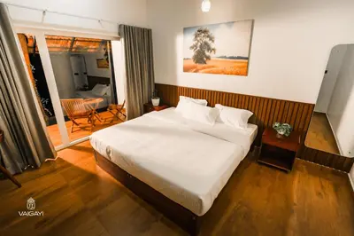 a bedroom with a large white bed and a balcony at Vaigayi Ayurveda Resort in Kodanad