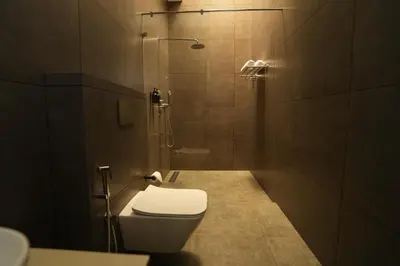 a small bathroom with a toilet and a shower at Vaigayi Ayurveda Resort in Kodanad