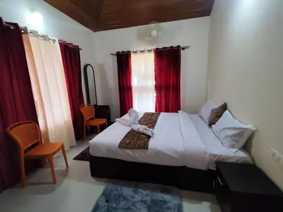 a bedroom with a white bed with red curtains at RajPari Stay in Madikeri