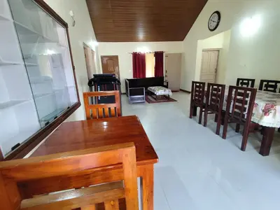 a living room with a wooden table and chairs at RajPari Stay in Madikeri