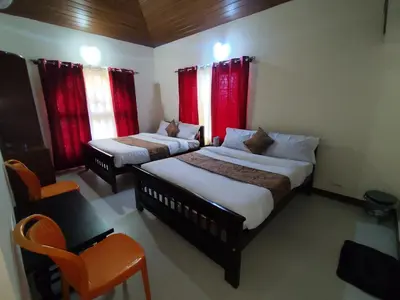 two beds in a room with red curtains at RajPari Stay in Madikeri