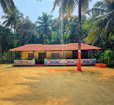 a house with a palm tree in front of it at Siruvani Forest Farmstay By Shivalaya Stays in Coimbatore